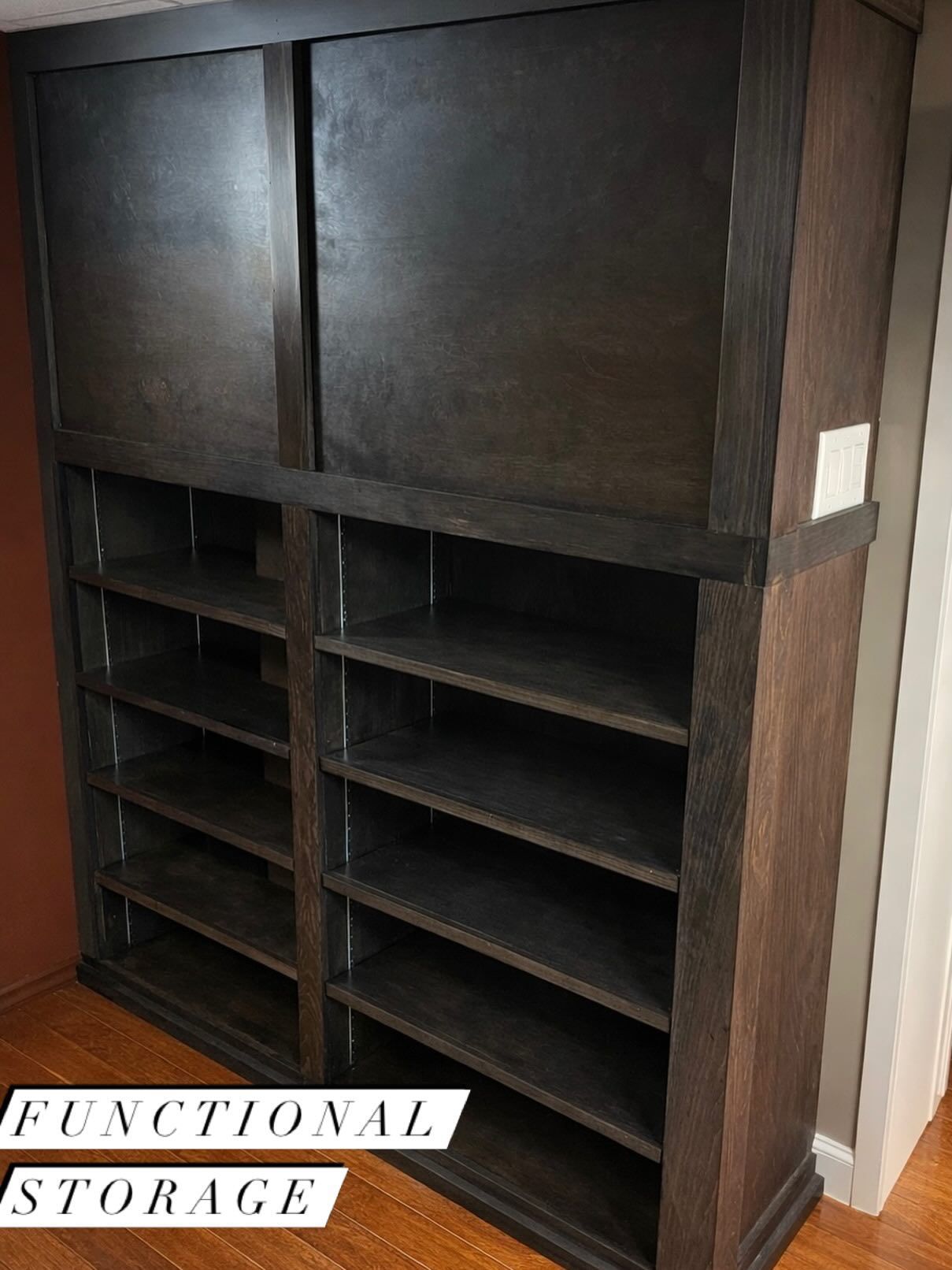 Black wooden shelving unit with cabinet doors and labeled storage compartments in a room