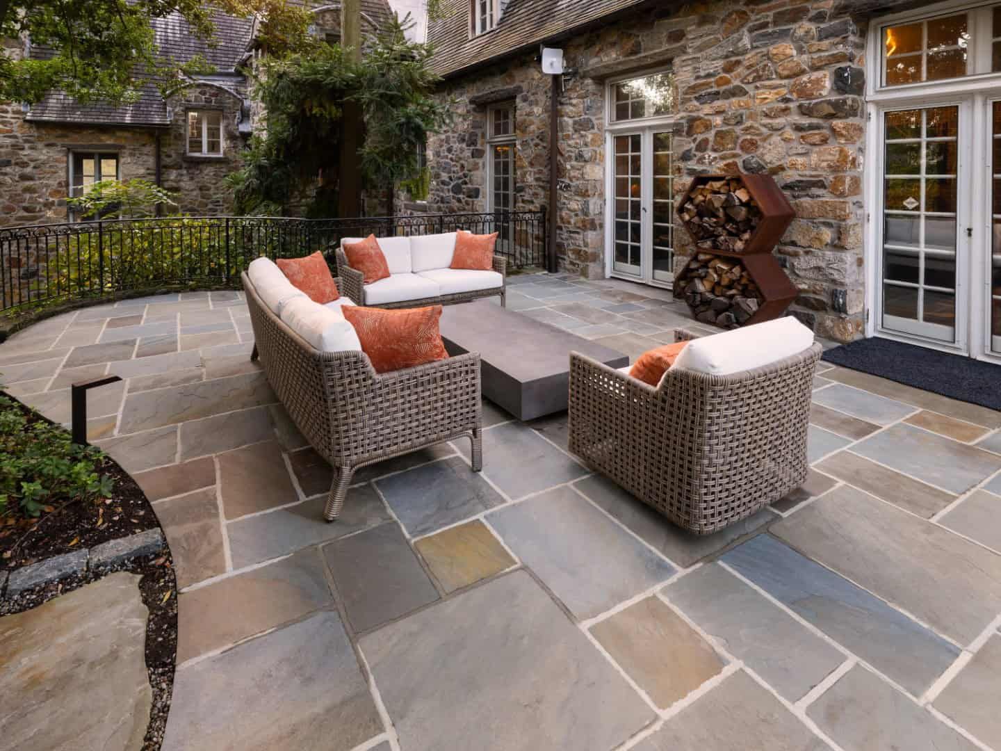Patio with wicker furniture, stone floor, and stone building in the background.