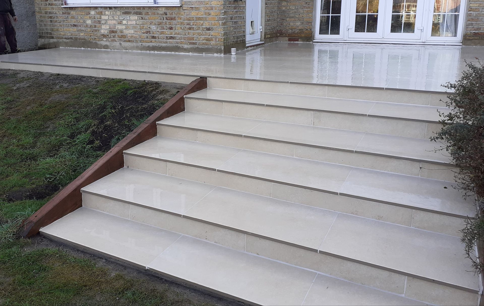 Stone steps leading up to a patio and a house with French doors.
