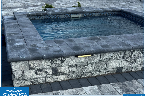 Stone hot tub with dark blue water on a paved patio
