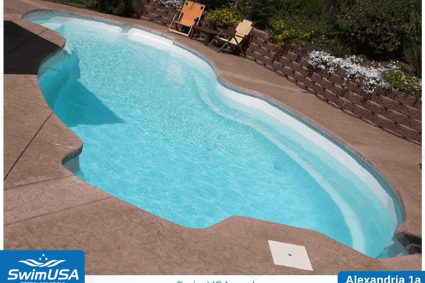 Curved backyard swimming pool with clear blue water and tan stone deck