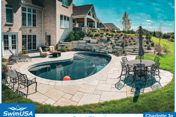 Luxury backyard pool with stone patio, outdoor seating, and landscaped garden beside a house