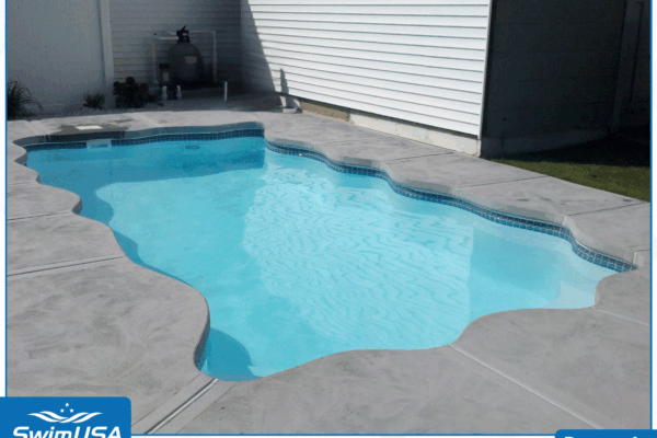 Backyard swimming pool with light blue water and a gray concrete deck beside a house