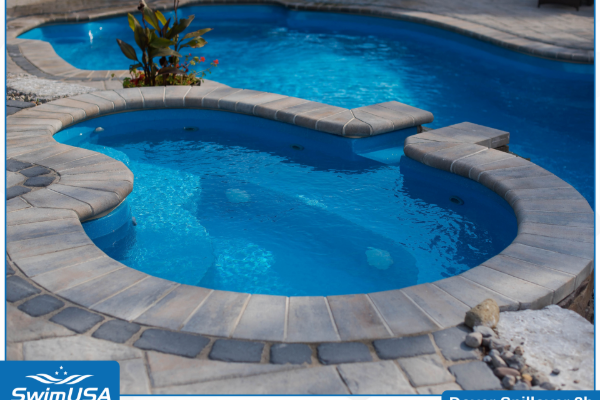 Backyard swimming pool with a raised, stone-lined hot tub and blue water