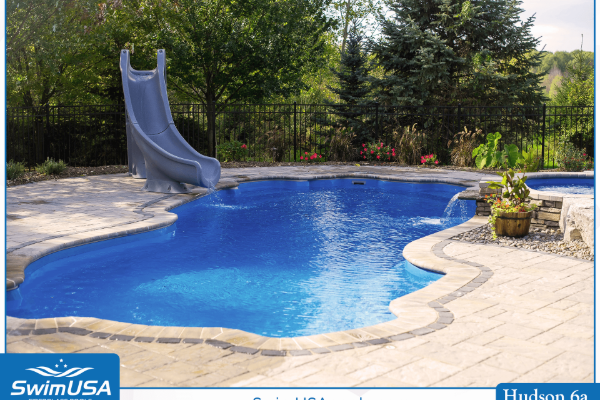 Backyard swimming pool with a slide, blue water, and stone patio surrounded by trees