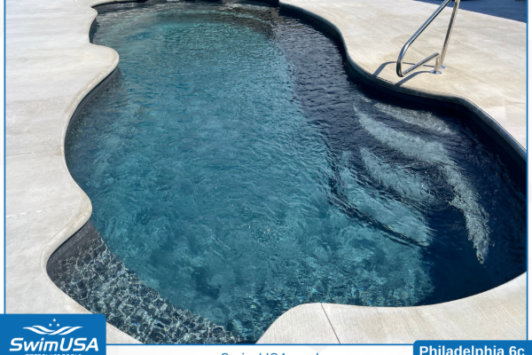 Curved blue swimming pool with white deck and metal ladder in sunlight