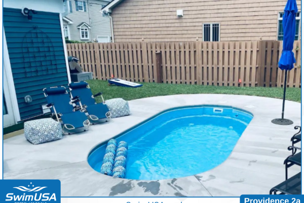 Backyard with a small blue inground pool, lounge chairs, umbrella, and wooden fence
