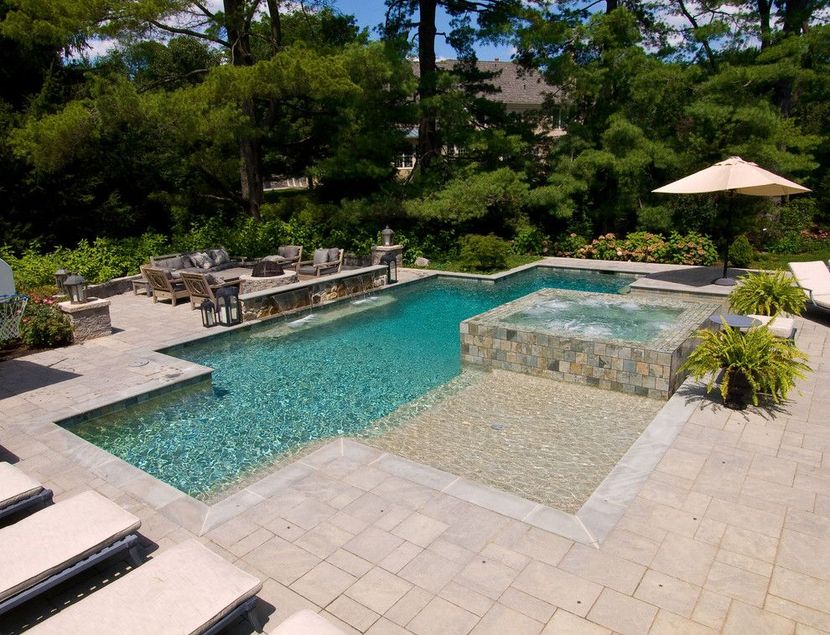 Backyard pool with turquoise water, spa ledge, stone patio, lounge chairs, and a patio umbrella