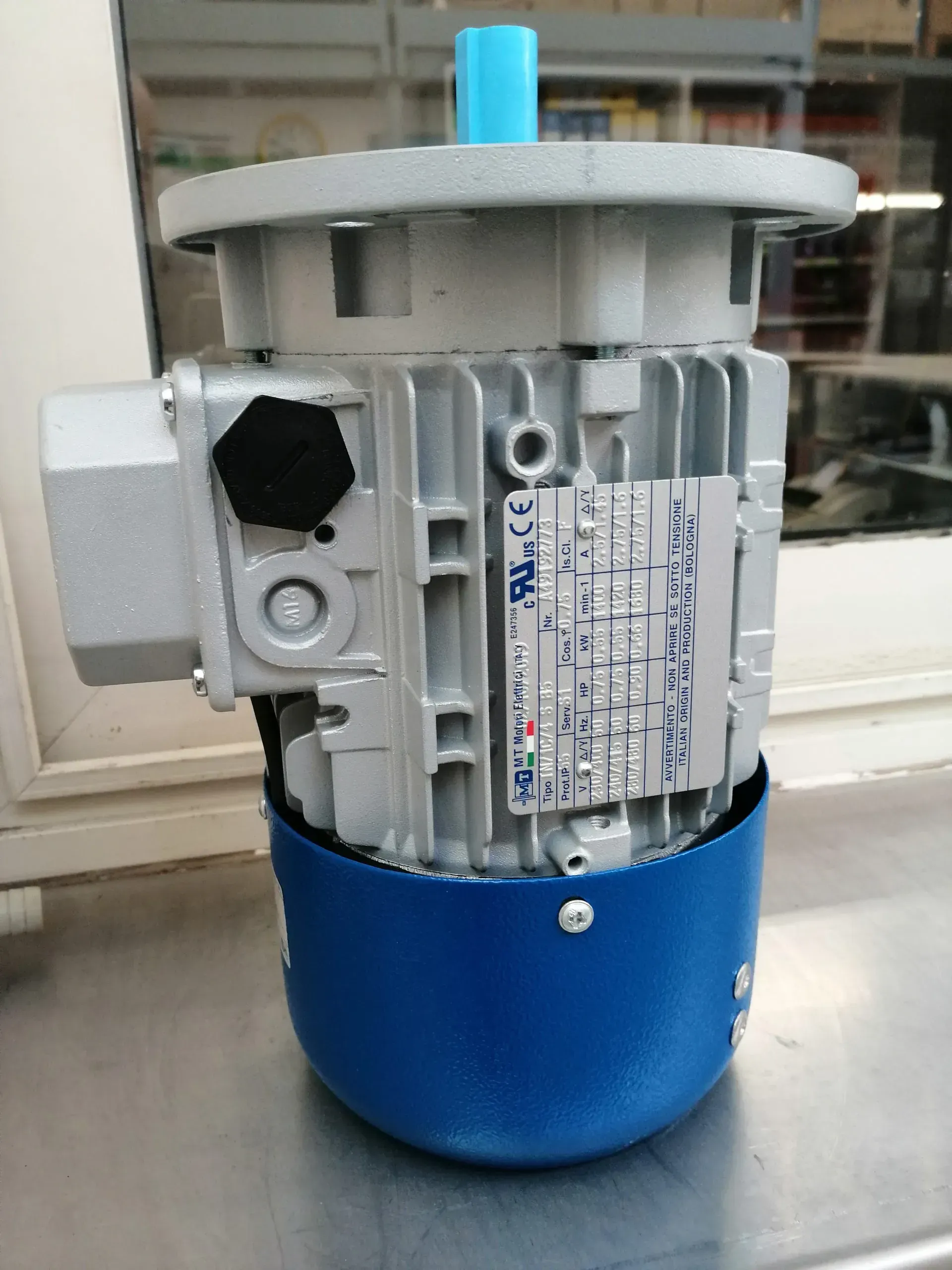 Motore elettrico con corpo argentato e base blu, montato su una superficie.