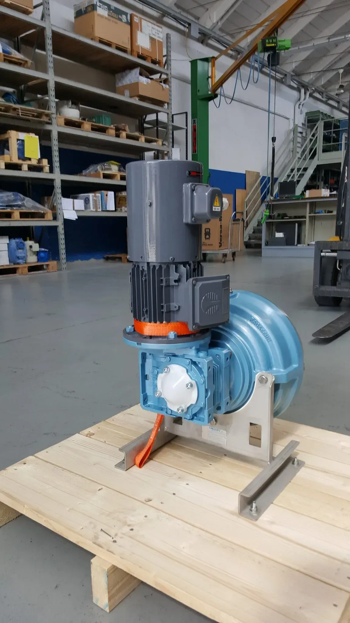 Soffiatore industriale blu con motore grigio su un pallet di legno in un magazzino.