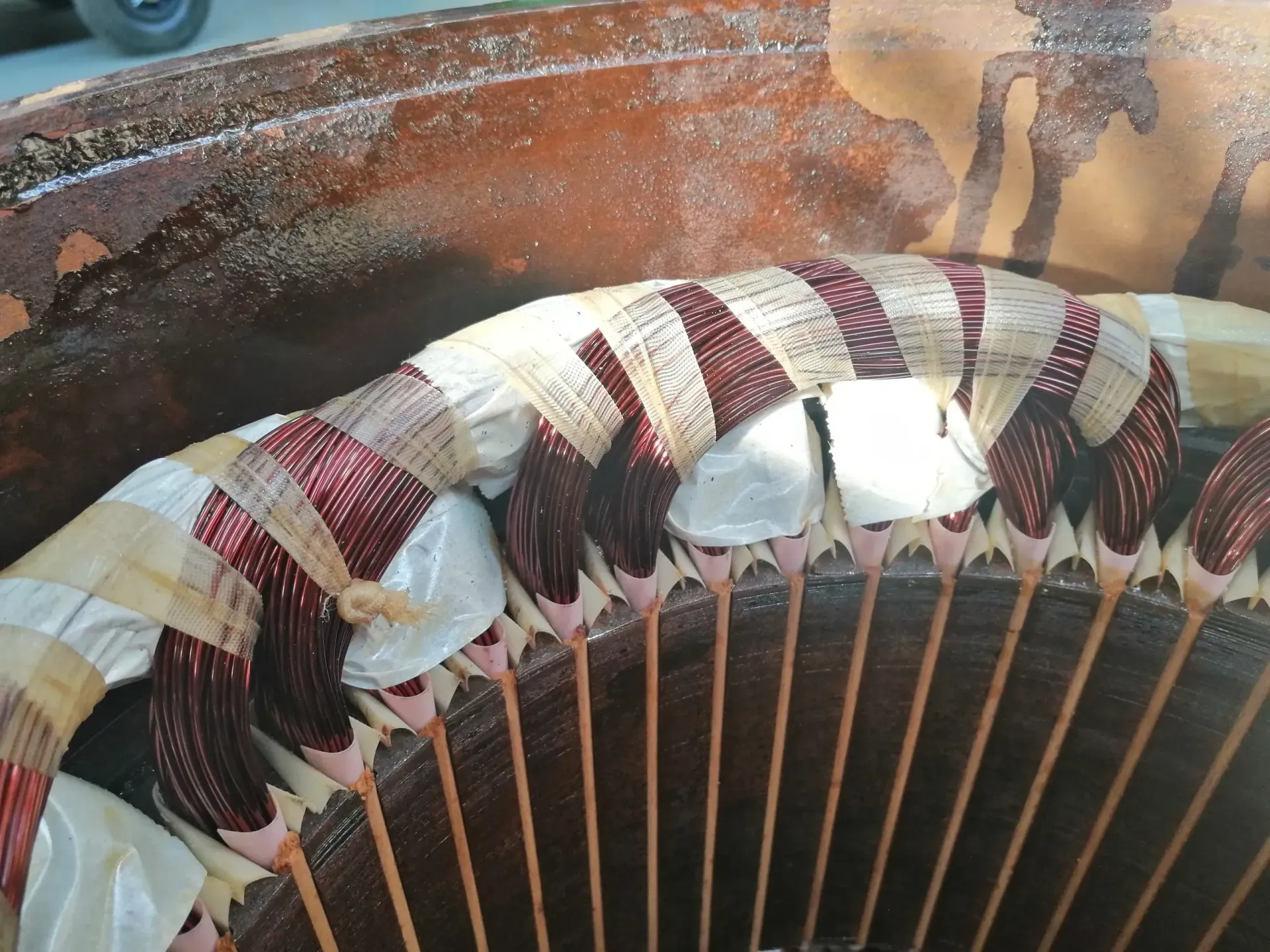 Primo piano dello statore del motore elettrico con avvolgimenti in rame e isolamento visibili all'interno di un alloggiamento metallico.