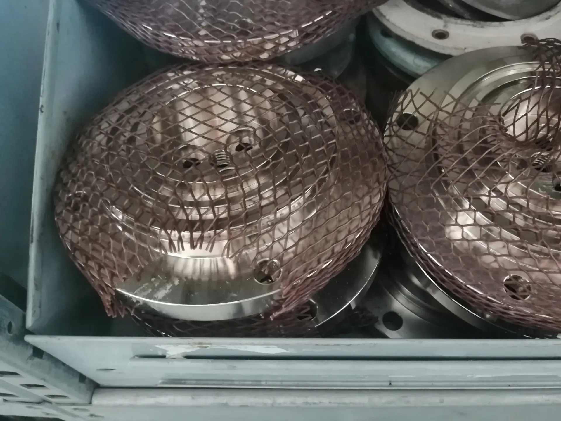 In un vassoio ci sono diversi oggetti metallici circolari color rame, ognuno dei quali è ricoperto da una rete.