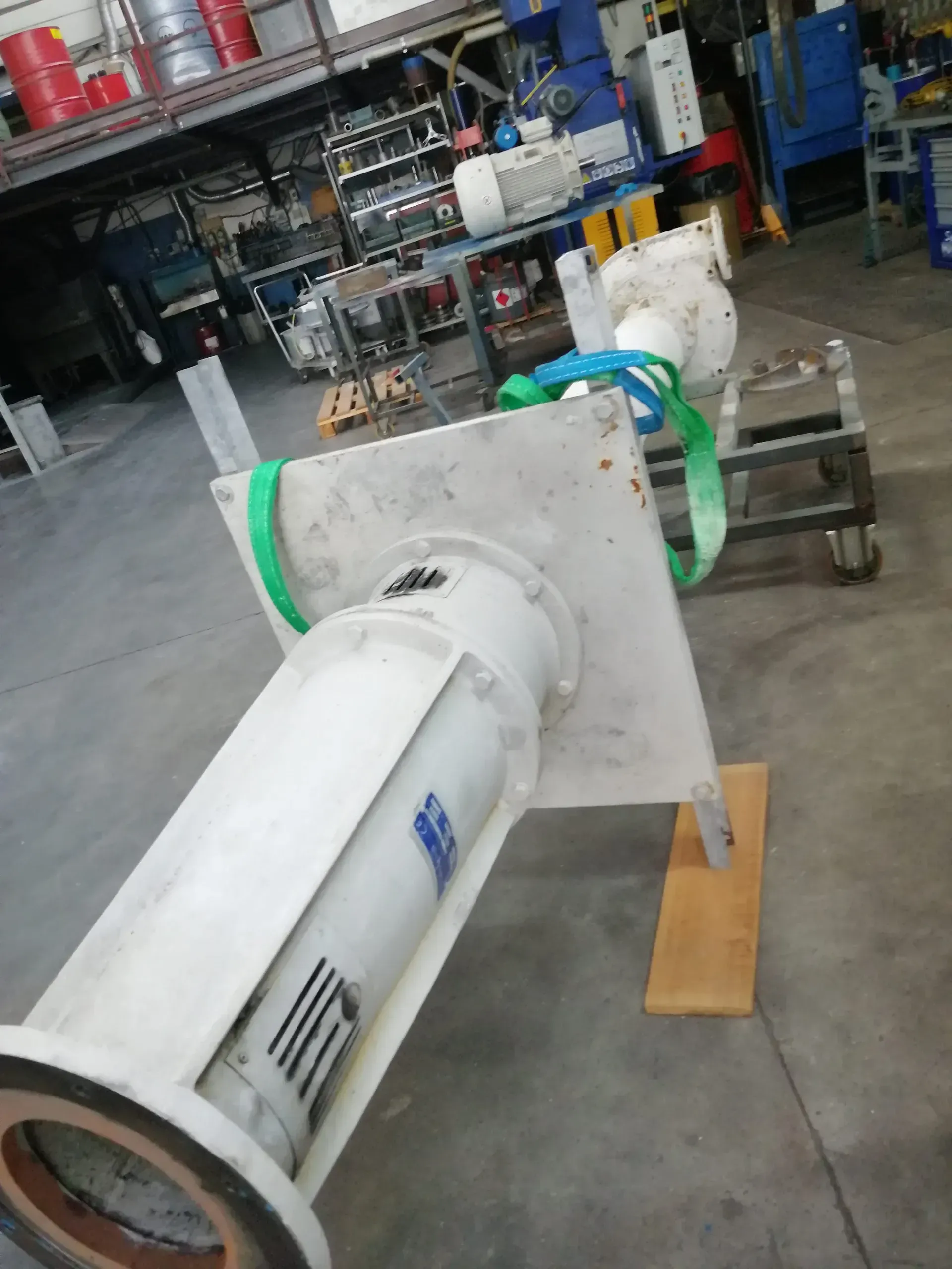 Grande gruppo pompa bianco sul pavimento di un'officina, fissato con cinghie.