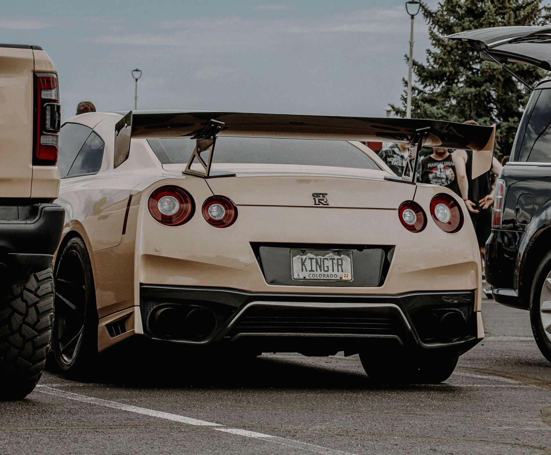 A white sports car is parked in a parking lot next to a truck.