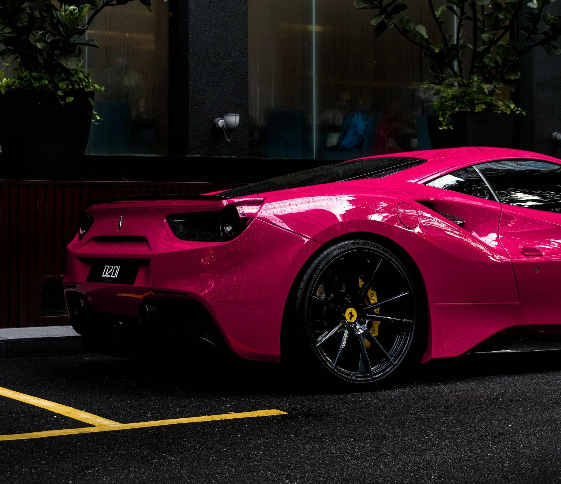 A pink sports car is parked in a parking lot