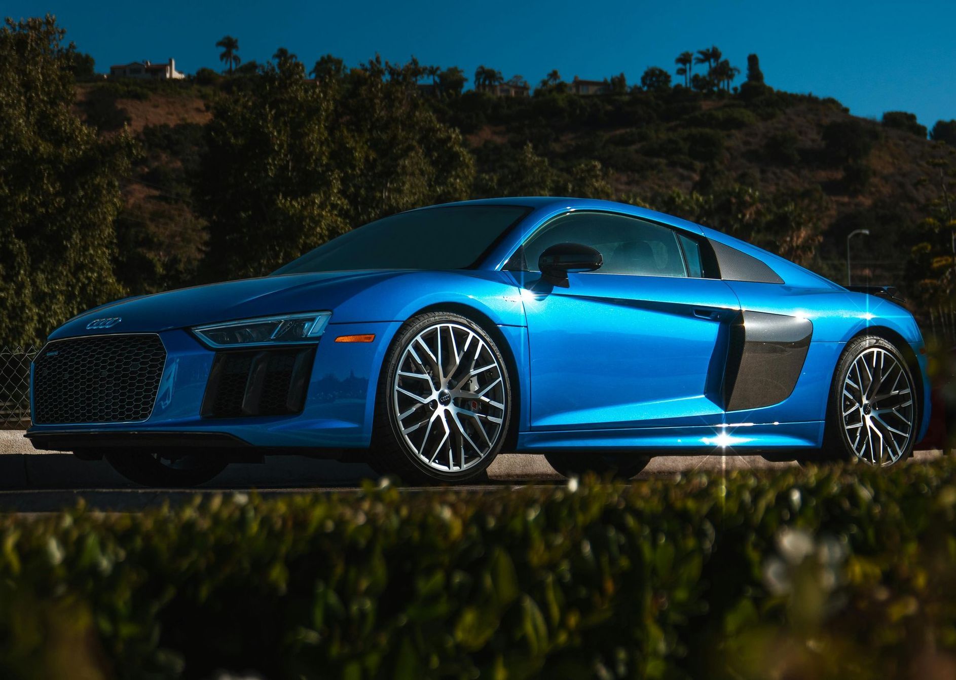 A blue audi r8 is parked on the side of the road.