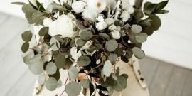 White and eucalyptus bouquet in a woven basket on a light floor