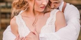 Couple embracing closely, with a woman in a white lace dress in the foreground