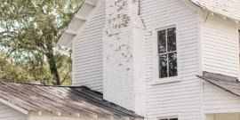 White house exterior with a chimney and old rustic decor