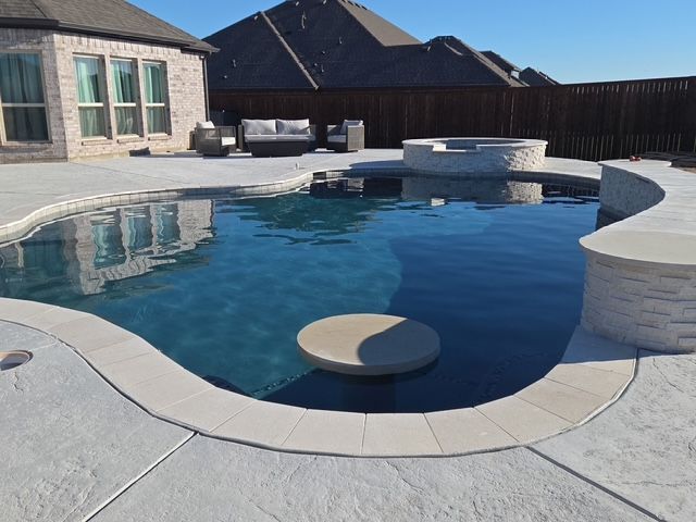 Pool with a swim-up bar, water features, and seating in a backyard.