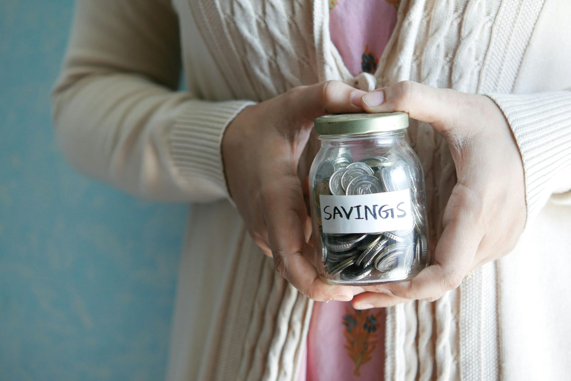 Hands holding a glass jar labeled “CAVING” with folded paper slips inside