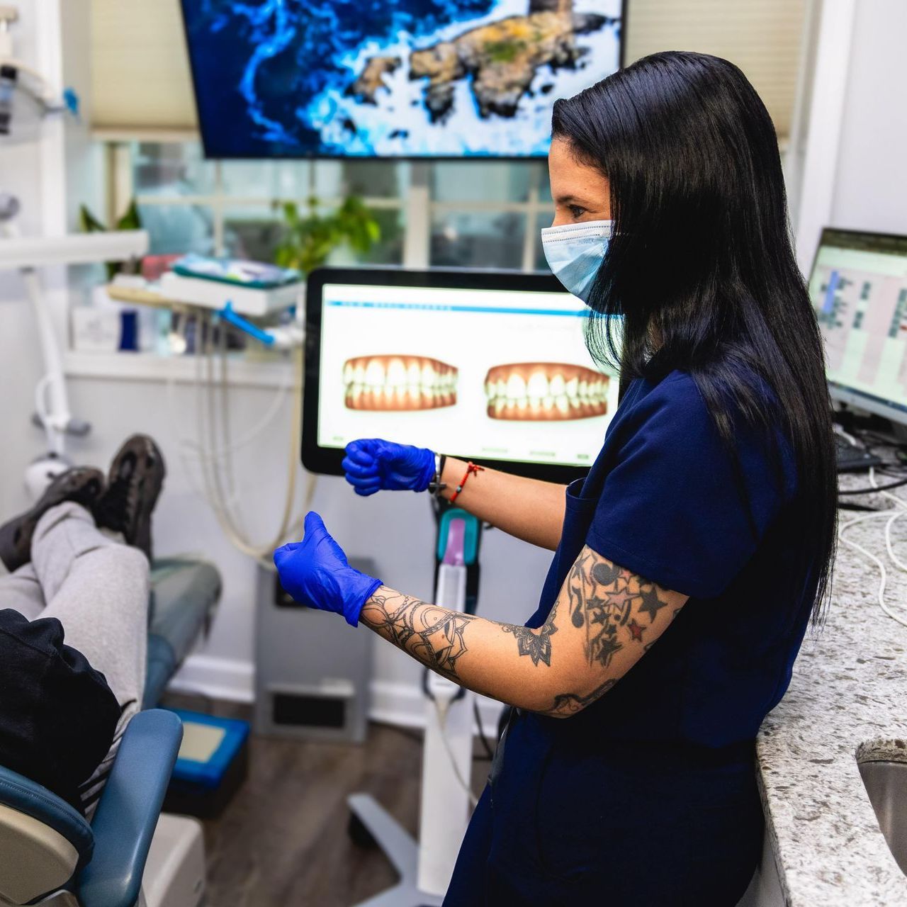 A dentist is talking to a patient in a dental office while holding a clipboard
