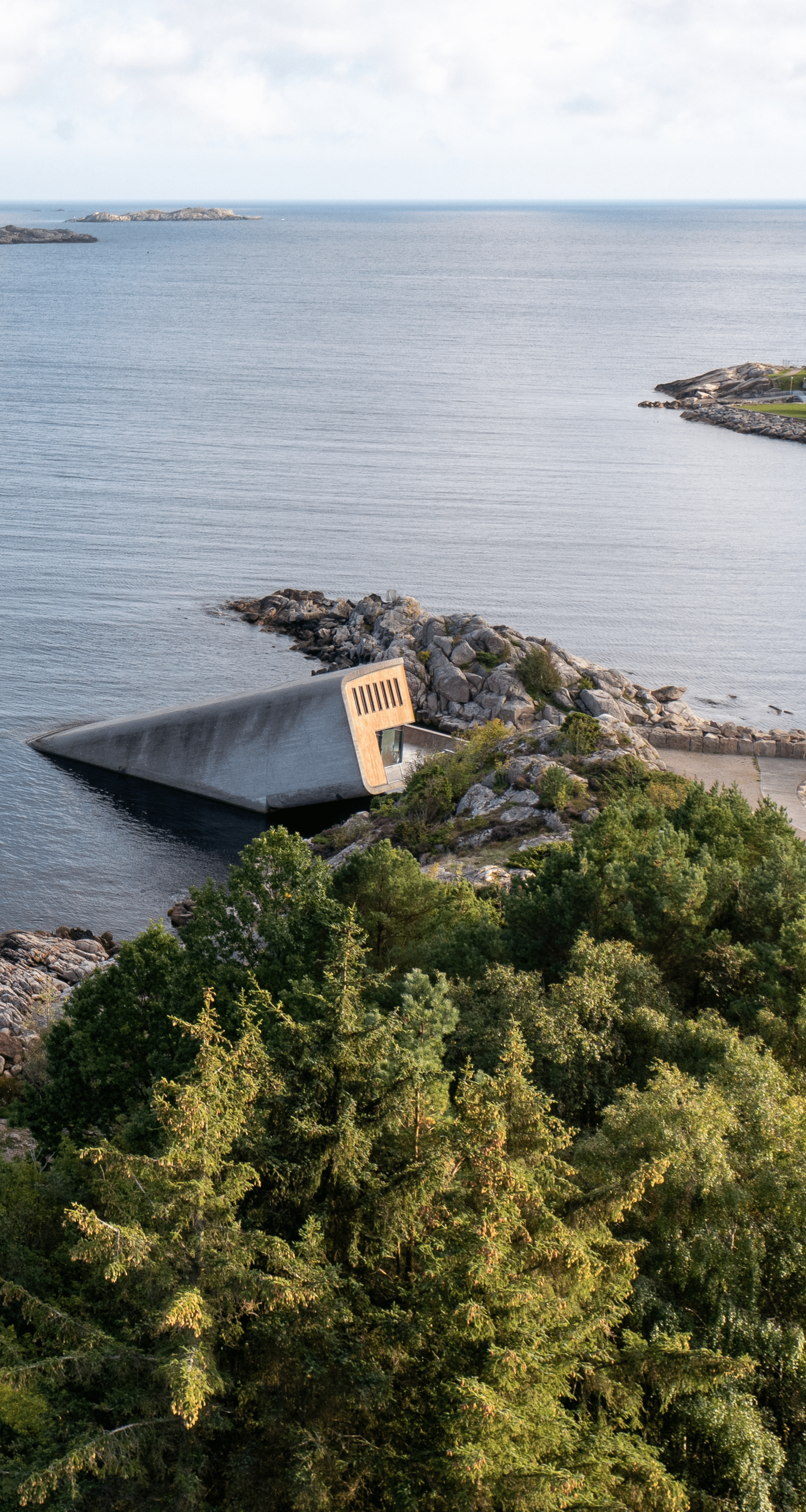 Concrete ramp slopes into the sea, next to a rocky shoreline, with ocean and distant islands in the background.