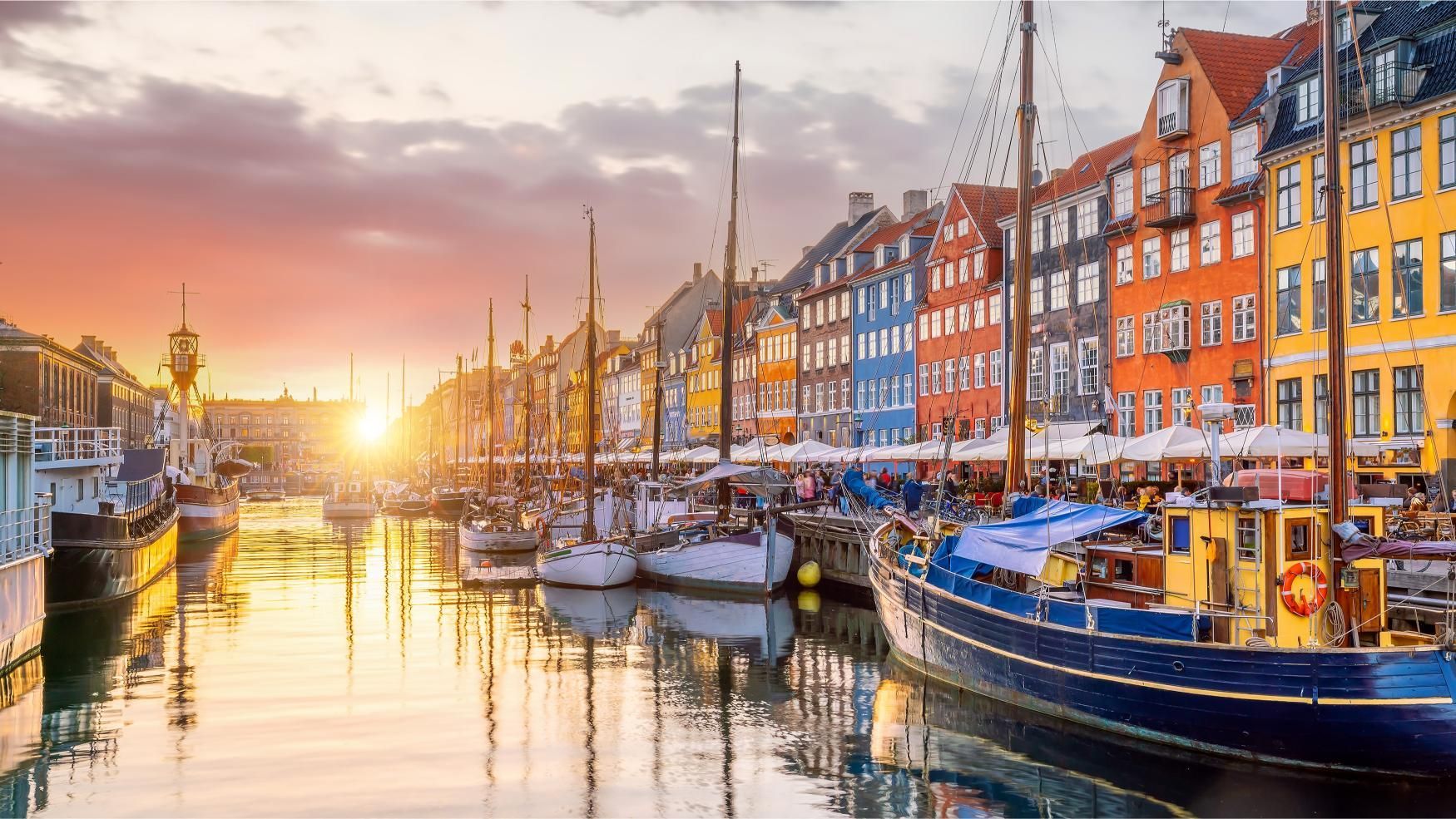 Sunset over a colorful canal lined with boats and historic buildings