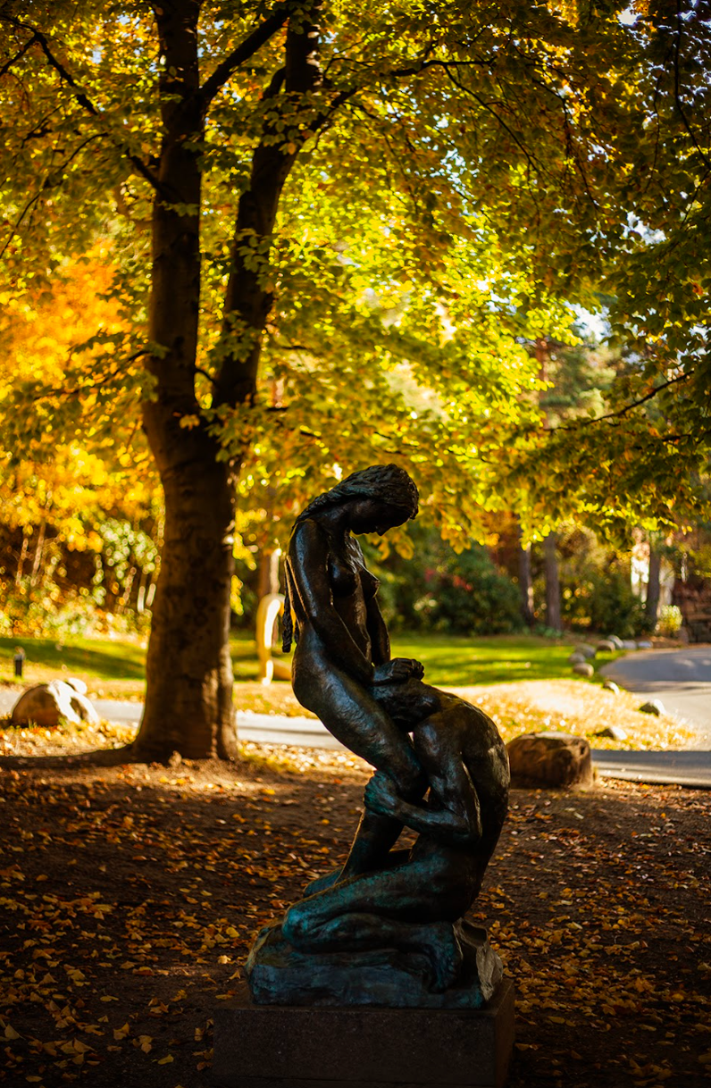 Bronze sculpture of figures embracing in a park with autumn foliage.
Photographer: Kristina Aurore Kvåle