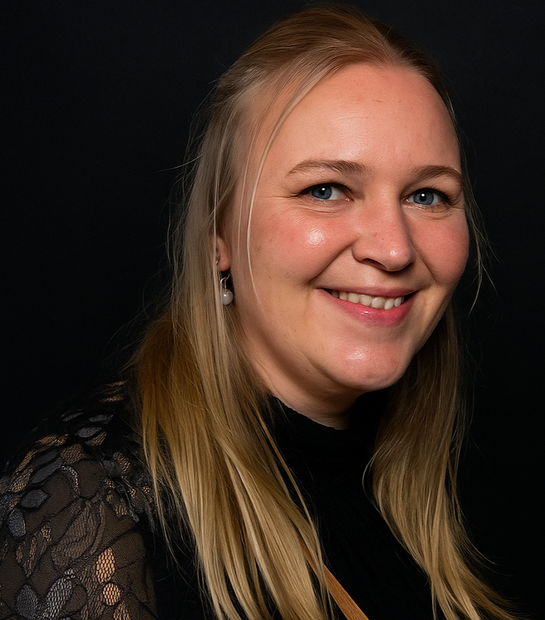 Lachende blonde vrouw in een zwart kanten topje tegen een donkere achtergrond