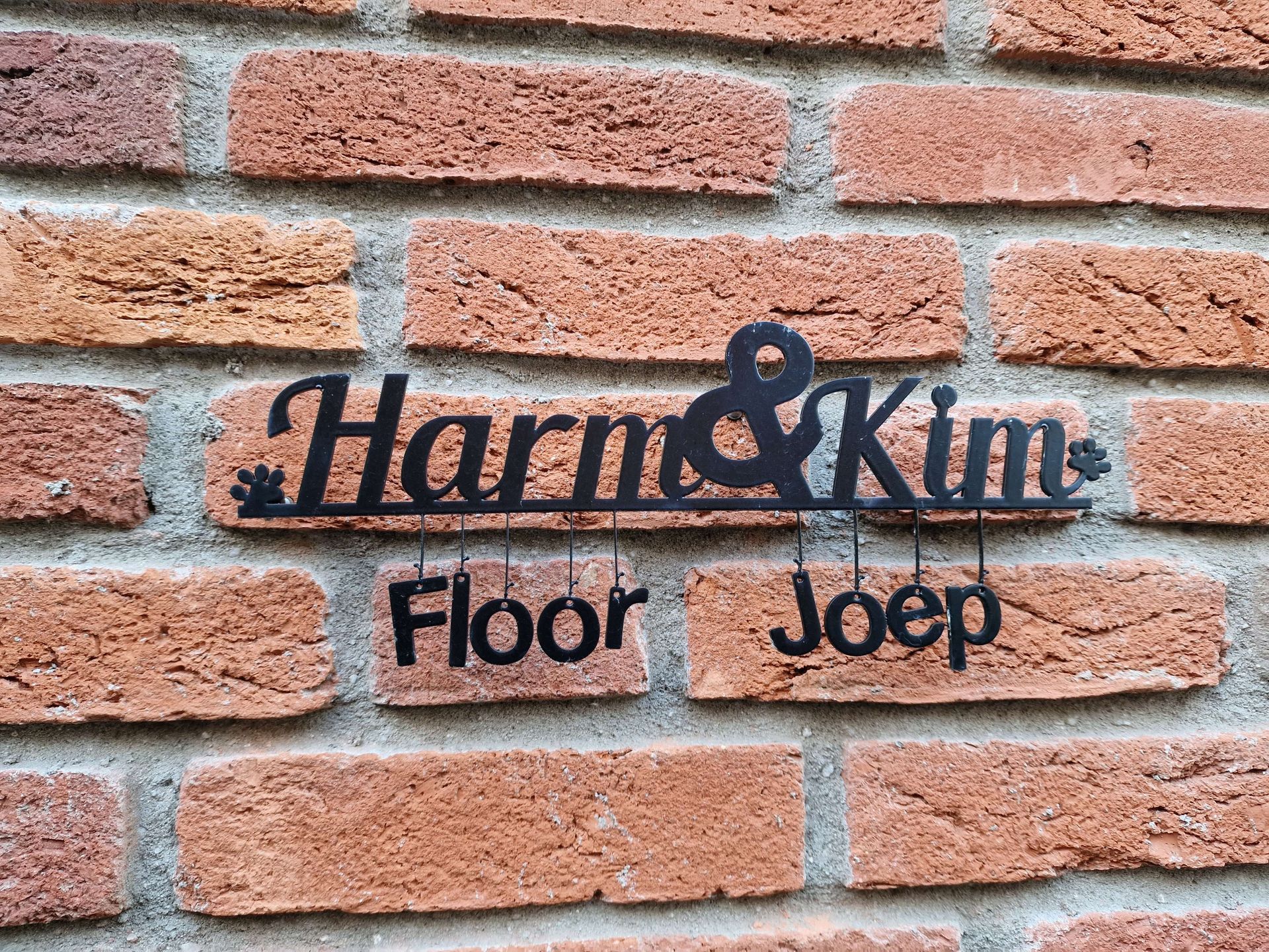 Zwart metalen bord op een bakstenen muur, 
