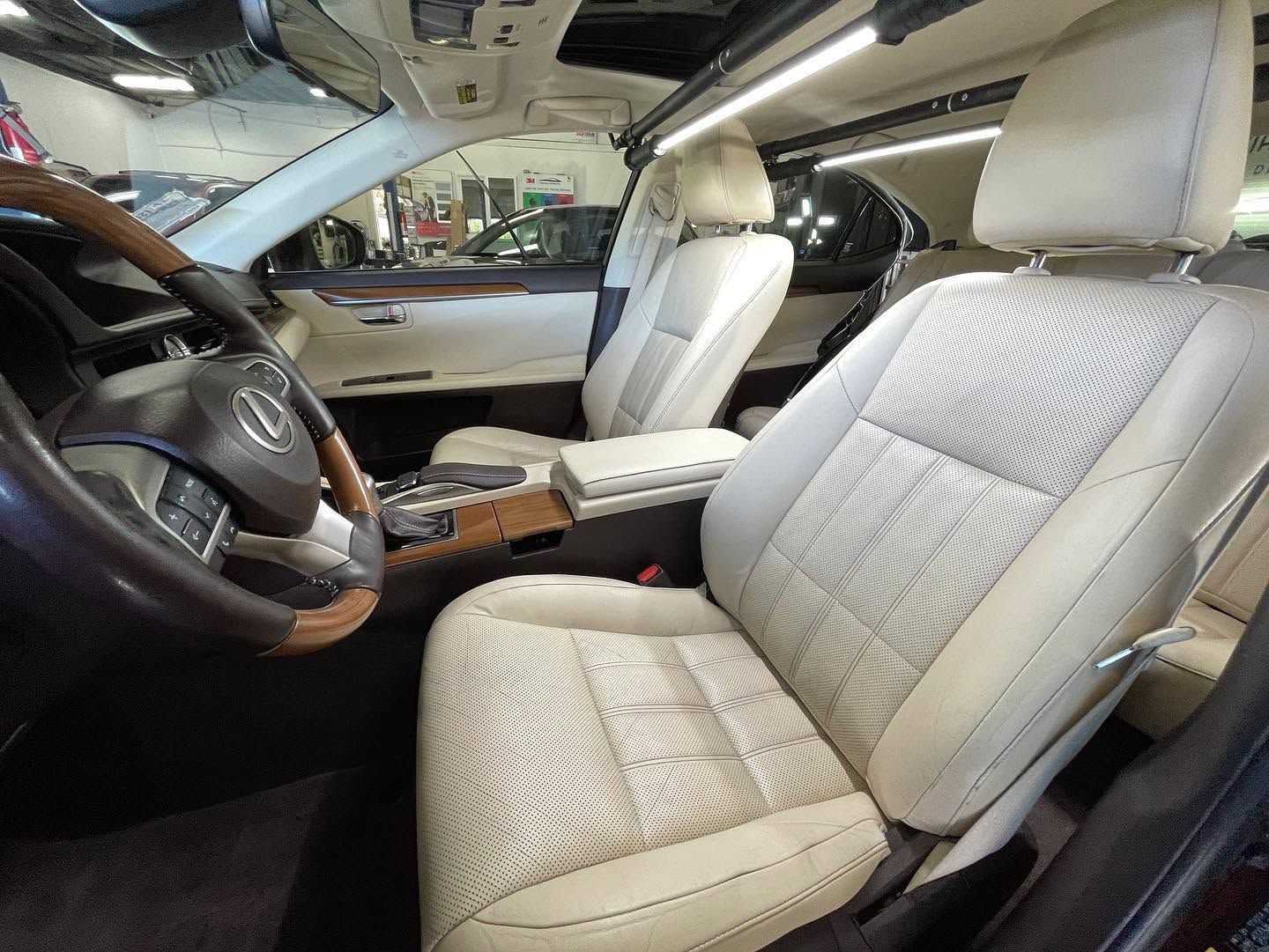 Car interior with beige leather seats, steering wheel, dashboard, and center console under a sunroof.