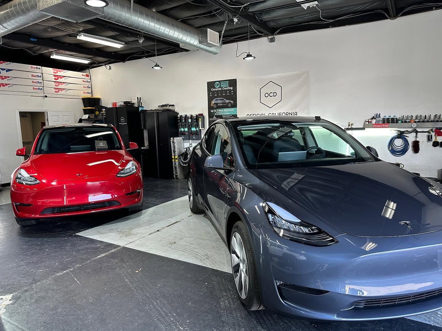 Two cars, a red SUV and blue sedan, parked inside a garage showroom