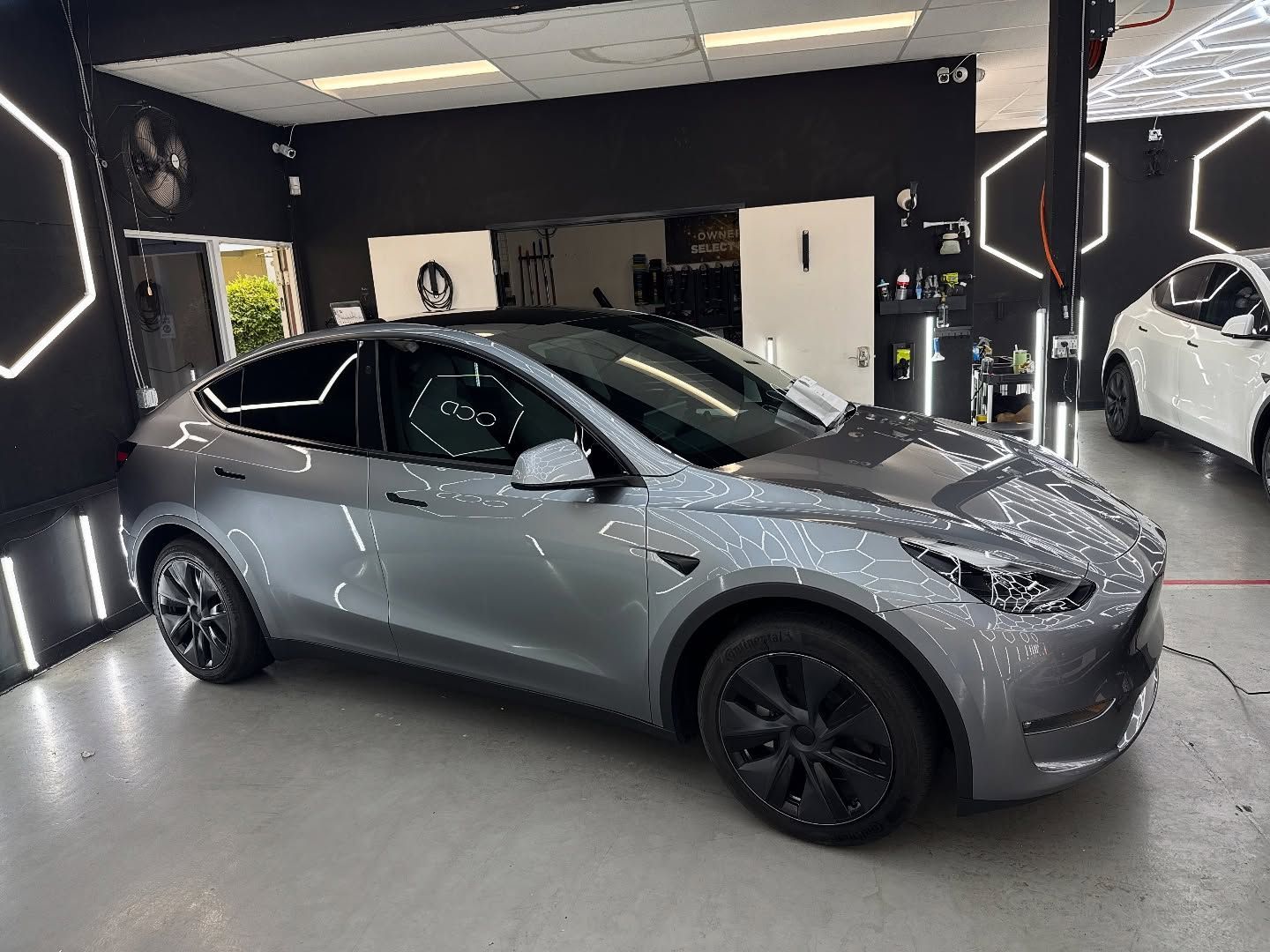 Gray Tesla sedan in a showroom with black walls and bright accent lighting