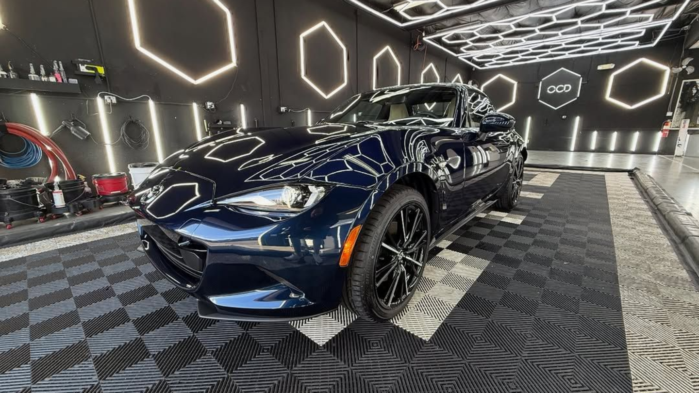 Blue sports car in a modern showroom with geometric LED wall lights and patterned floor