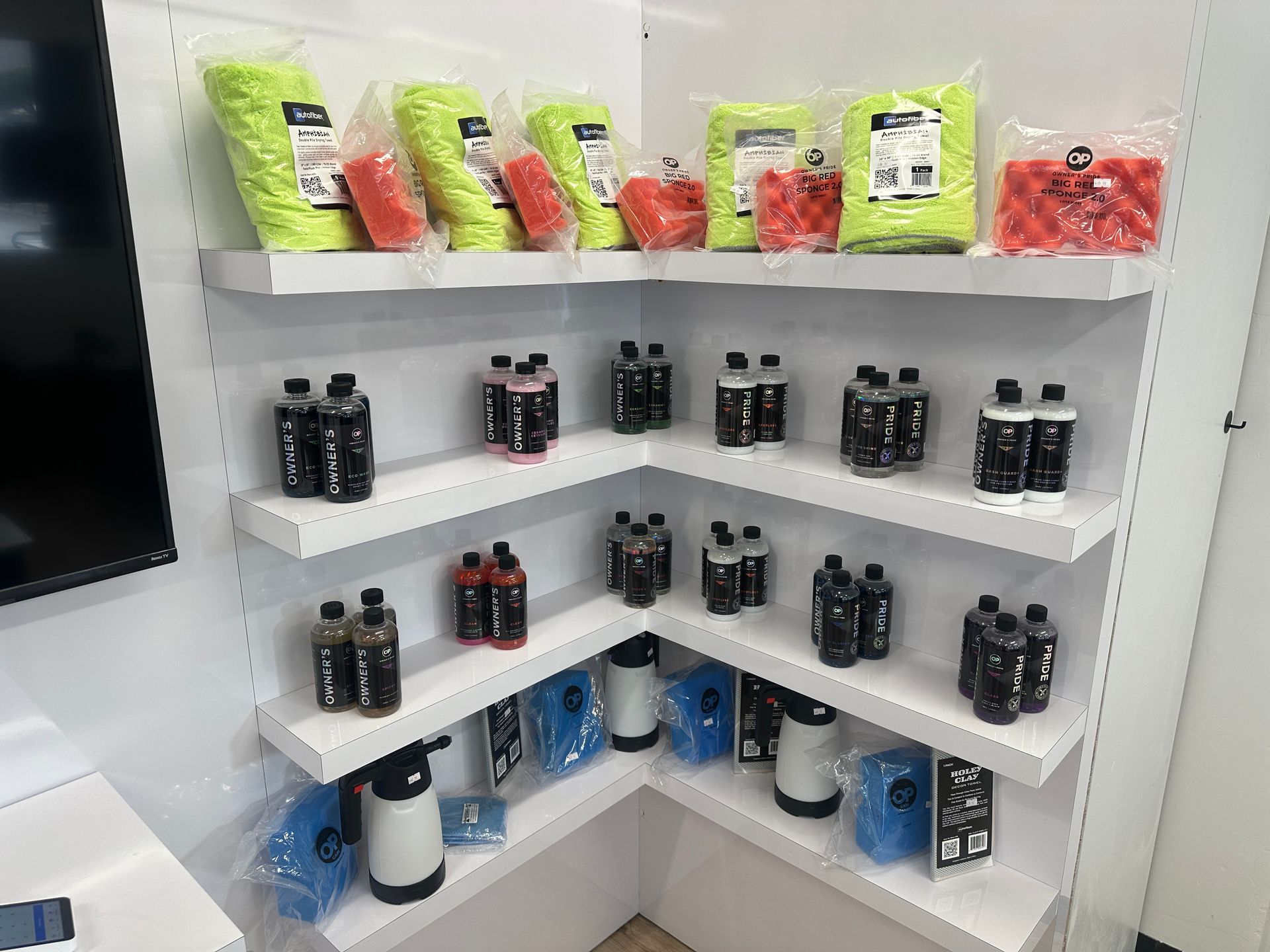 Corner store shelf with black bottles, red snacks, and lime-green packaged products in a white display unit