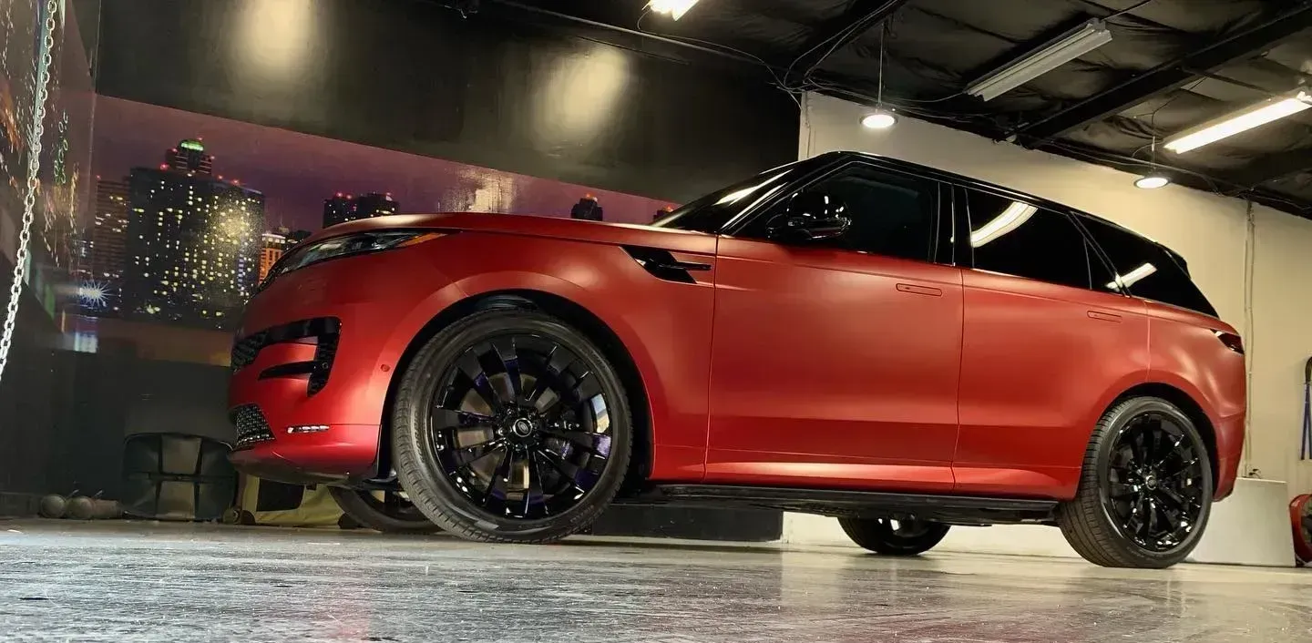 Red SUV parked in a dim garage, with black wheels and reflections on a wet floor.