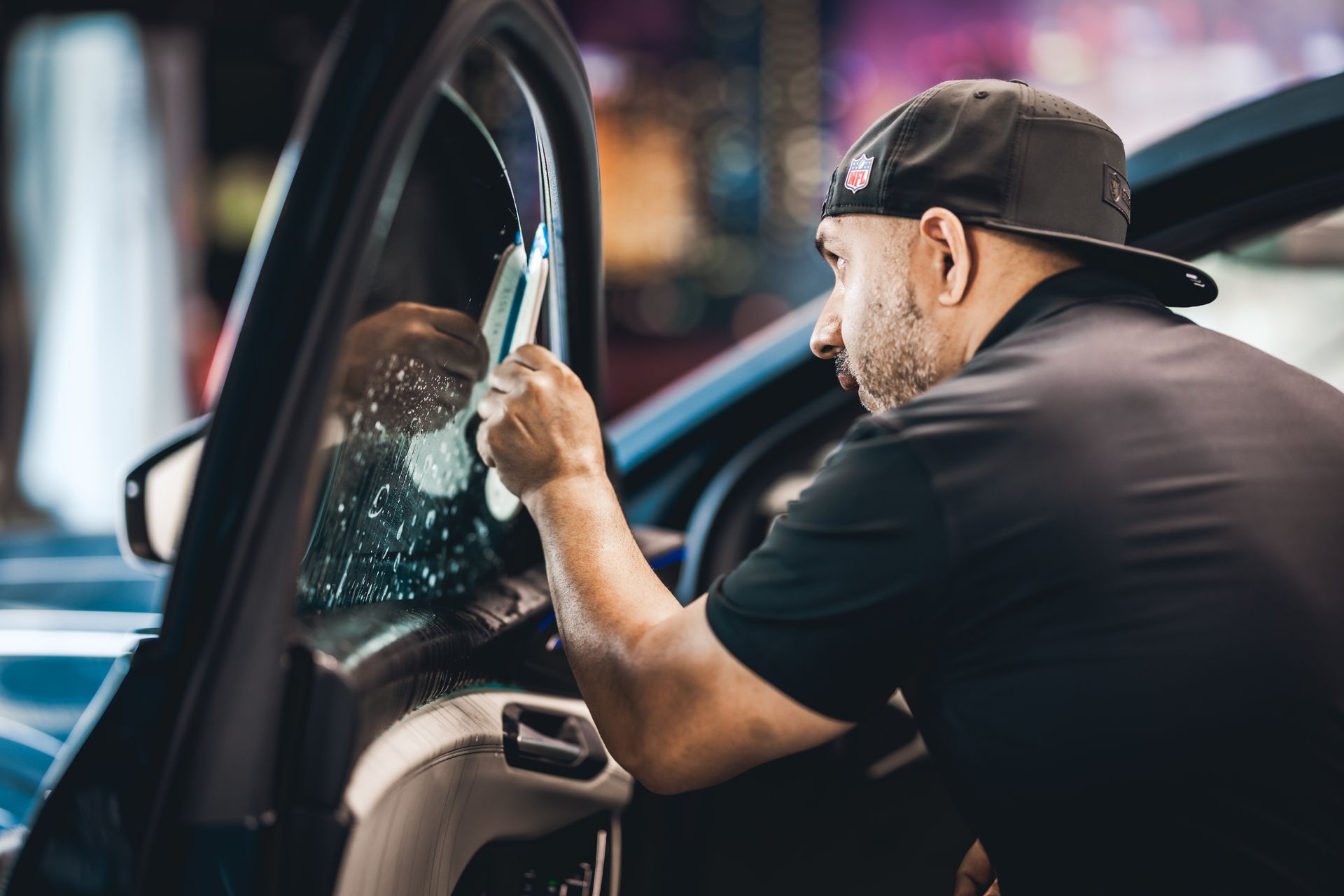 Man polishing a car window with a cloth in a detailing shop