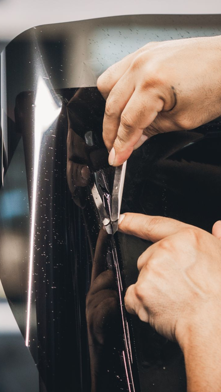 Person polishing a black car in a neon-lit garage with hexagonal wall lights