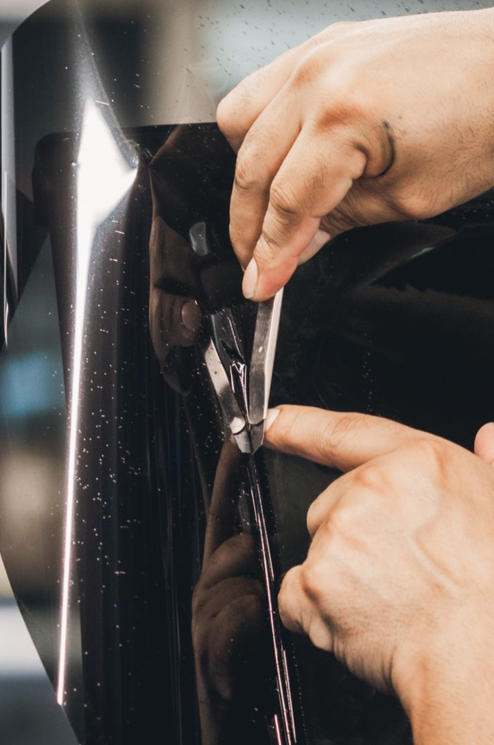Hands using a wrench to tighten a bolt on a black car door.