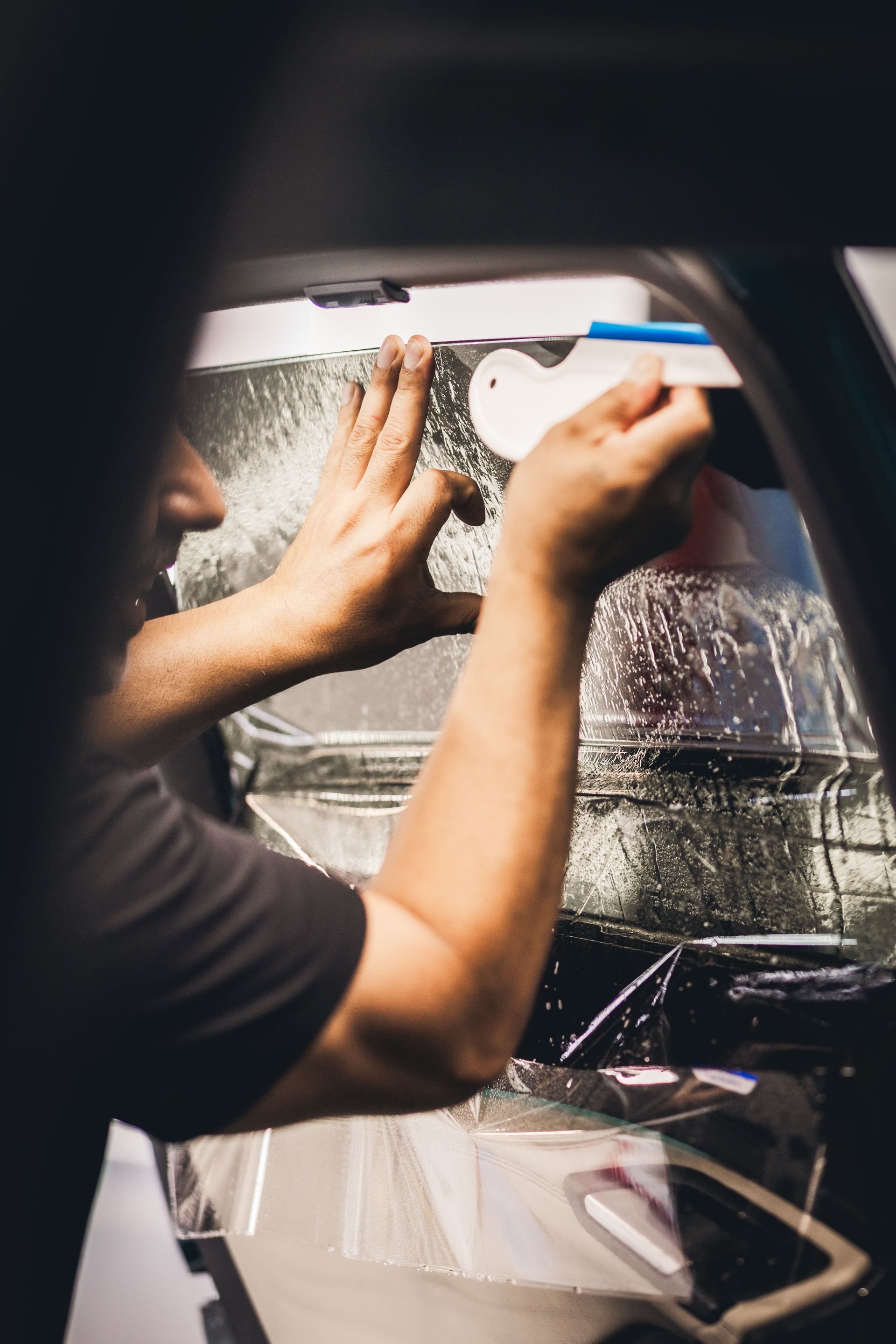 Person cleaning a black helmet with a blue cloth in a garage or workshop