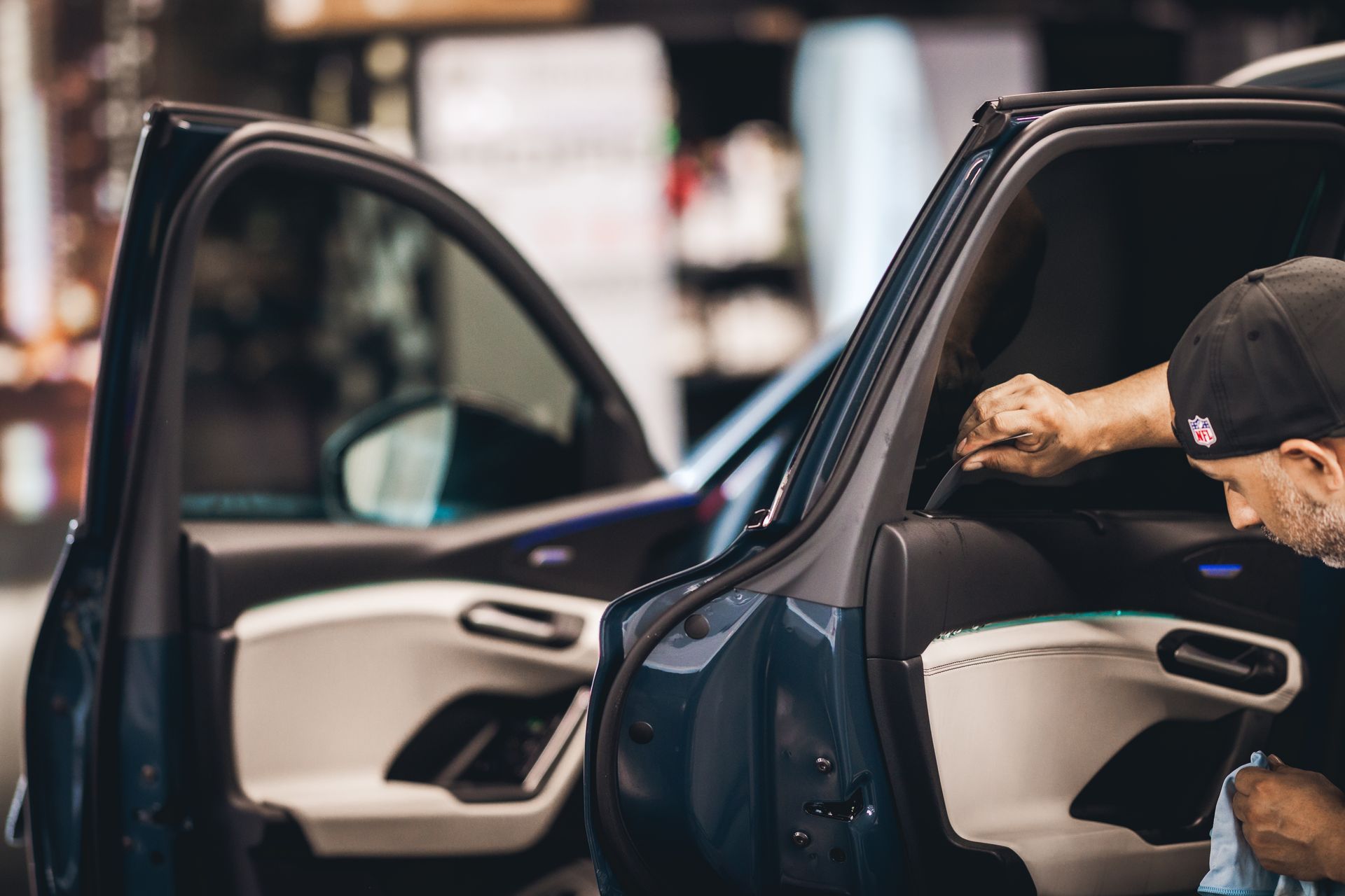 Man cleaning the interior of a black car with open doors