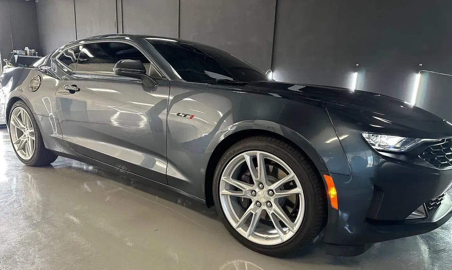 Gray sports car parked indoors under bright lights