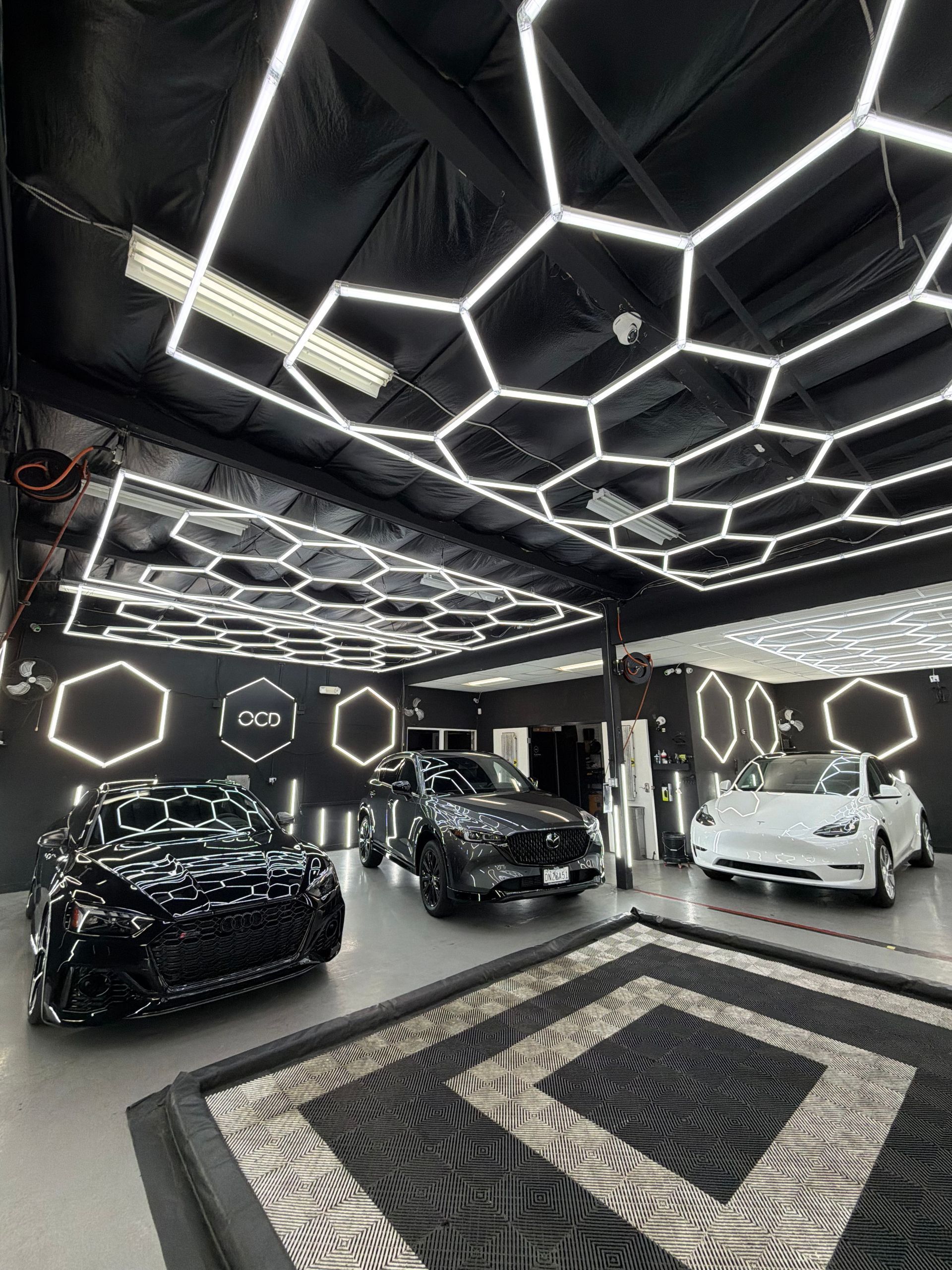 Luxury car showroom with black geometric LED ceiling and three cars on display