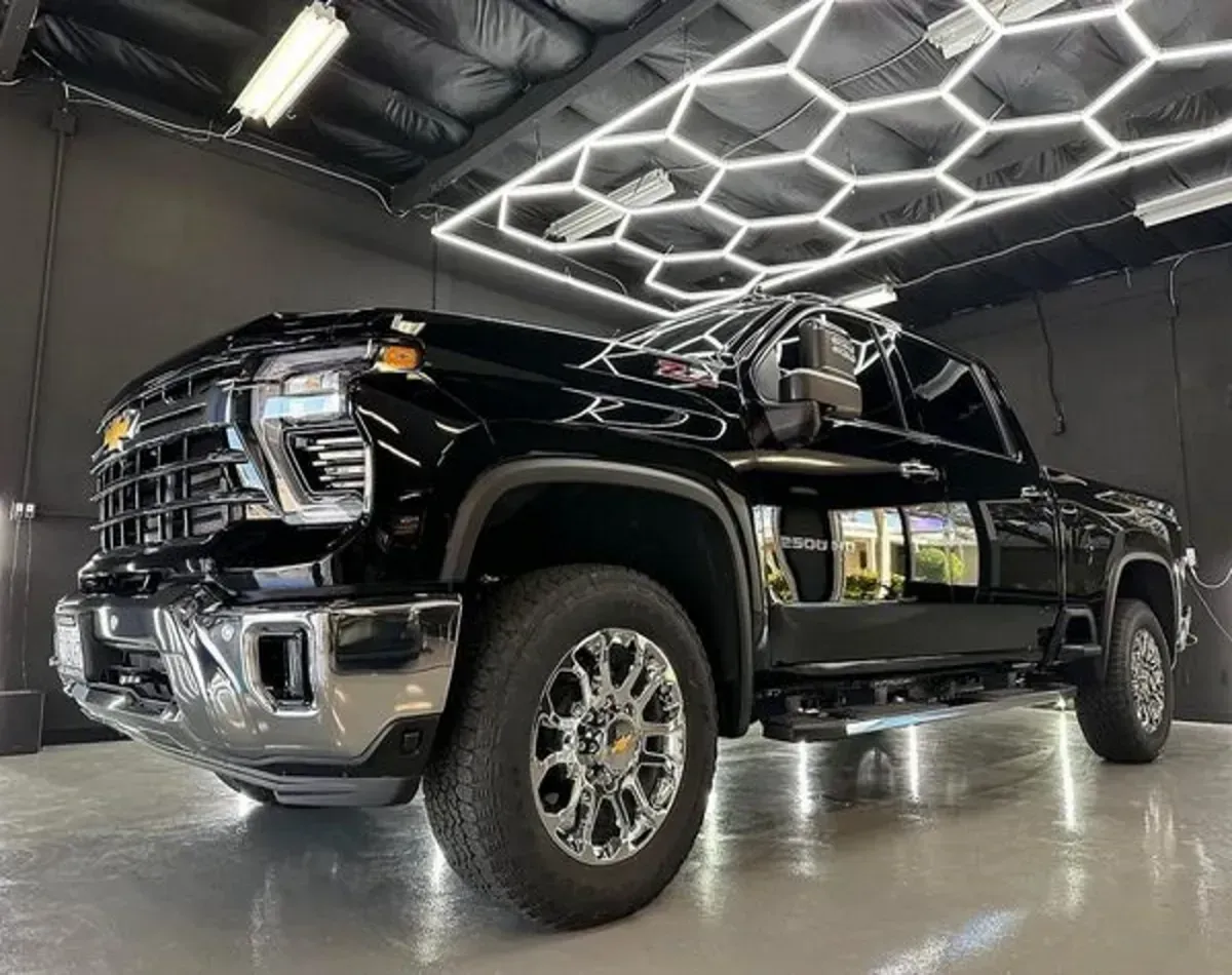 Black pickup truck in a showroom with bright hexagonal ceiling lights and polished floor