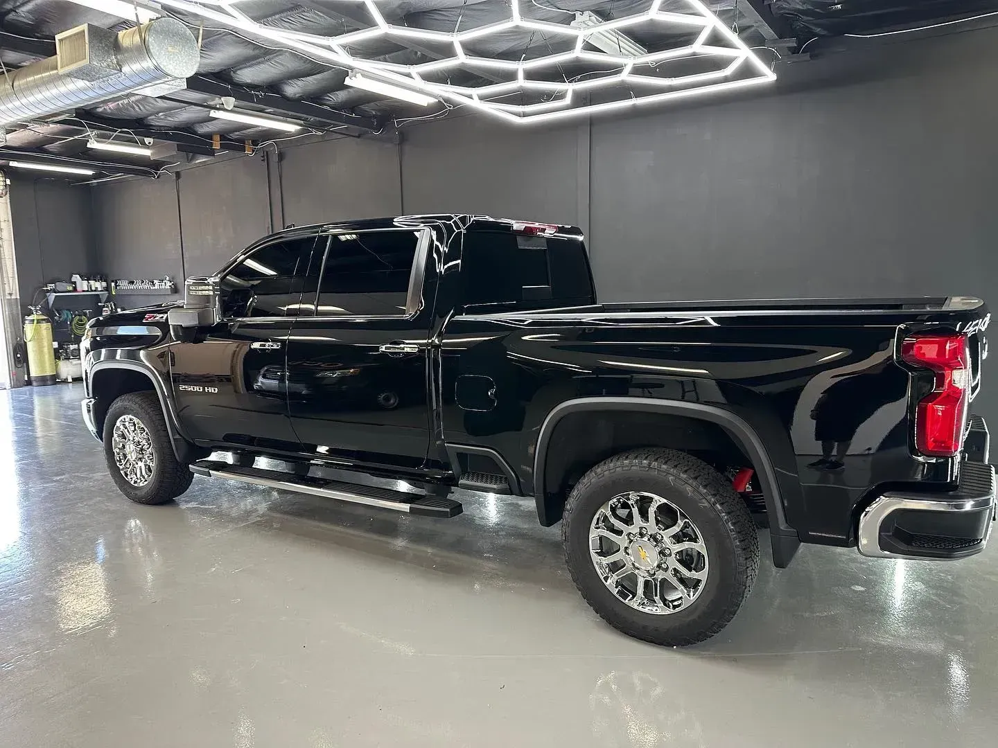Black pickup truck in a showroom under bright geometric ceiling lights.
