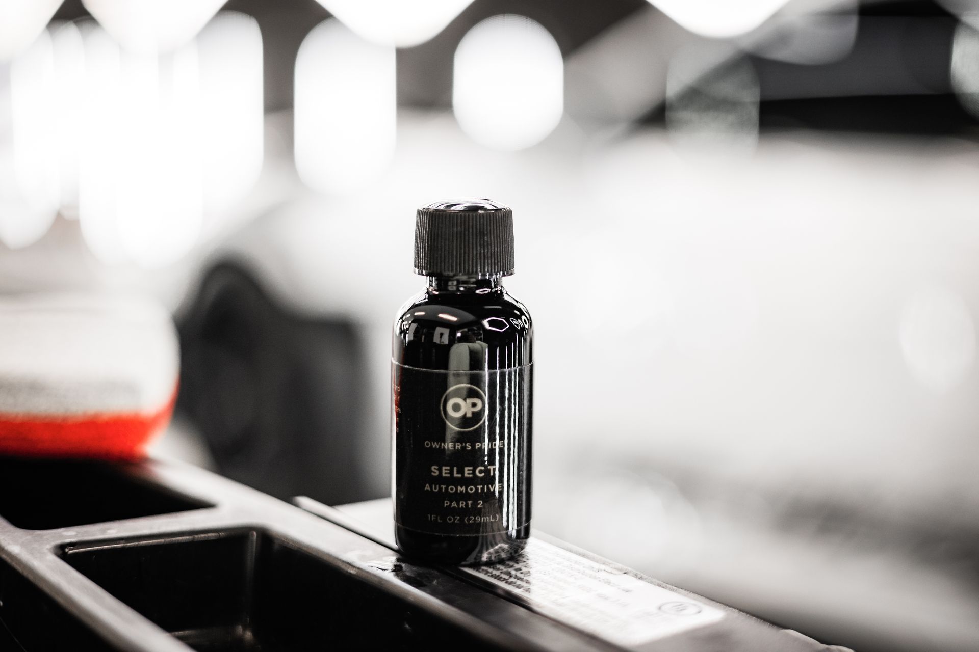 Small black bottle with a cap on a tray, photographed in a bright, blurred background.