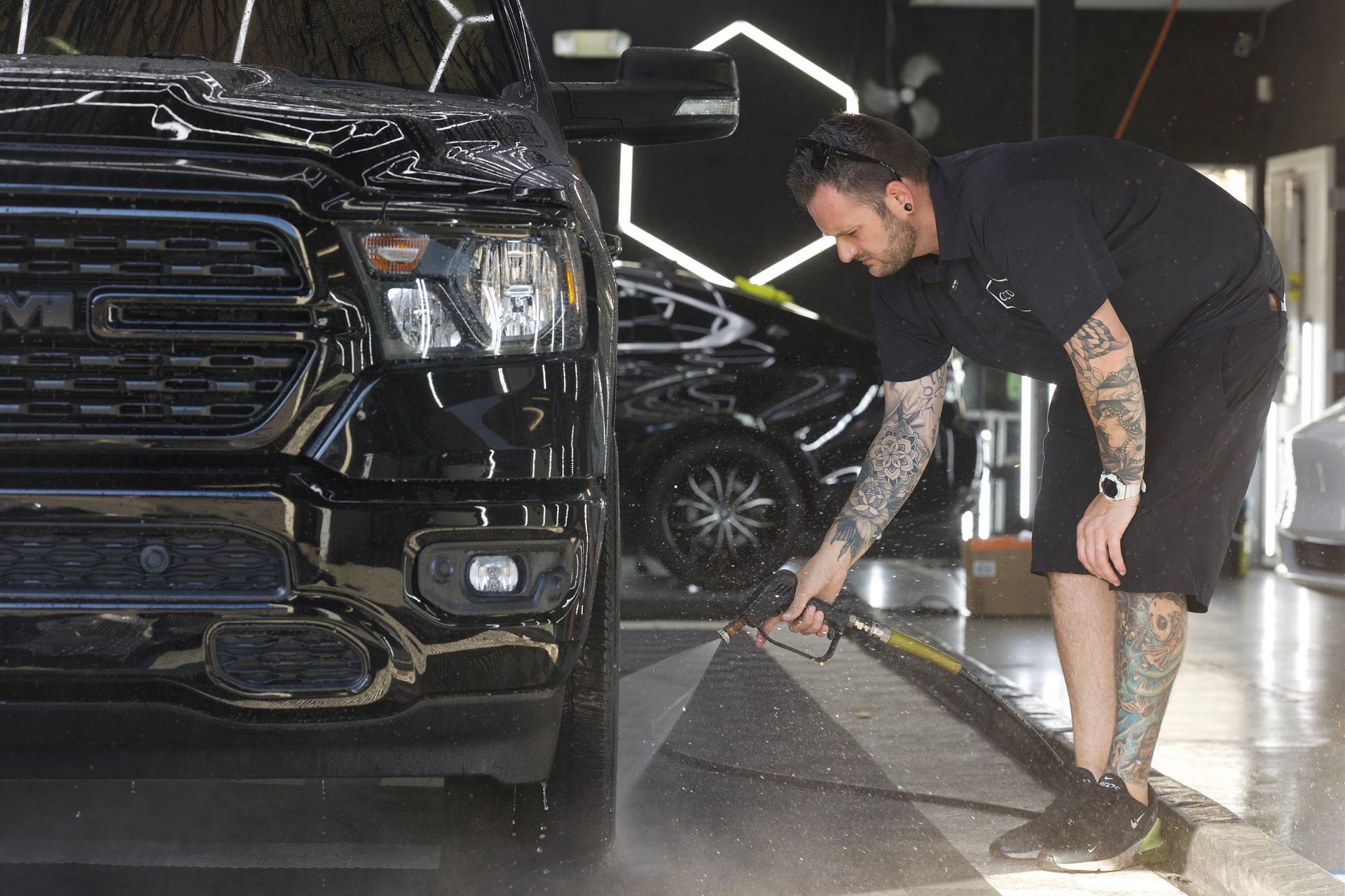 Person pressure-washing a black car wheel in a garage