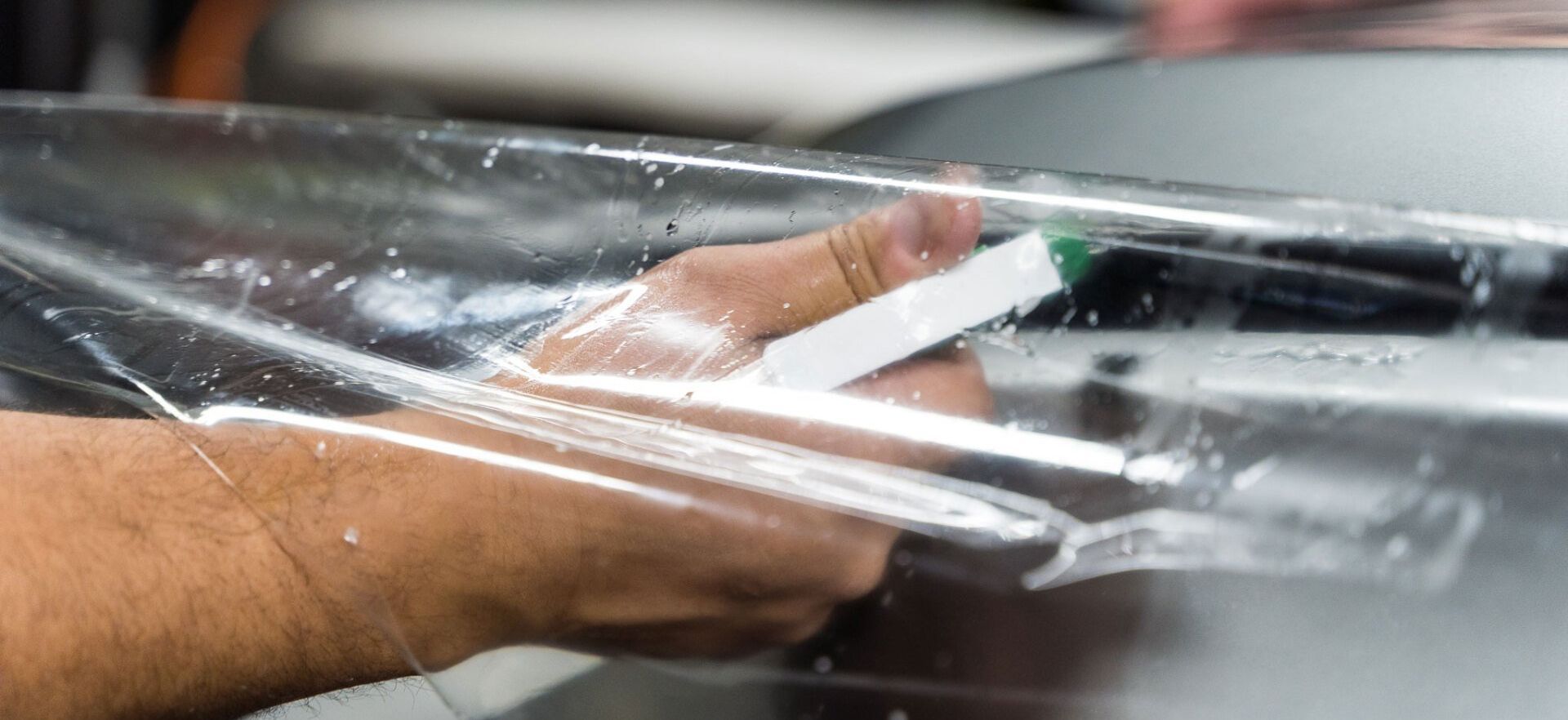 Hands wrapping clear plastic film around an object