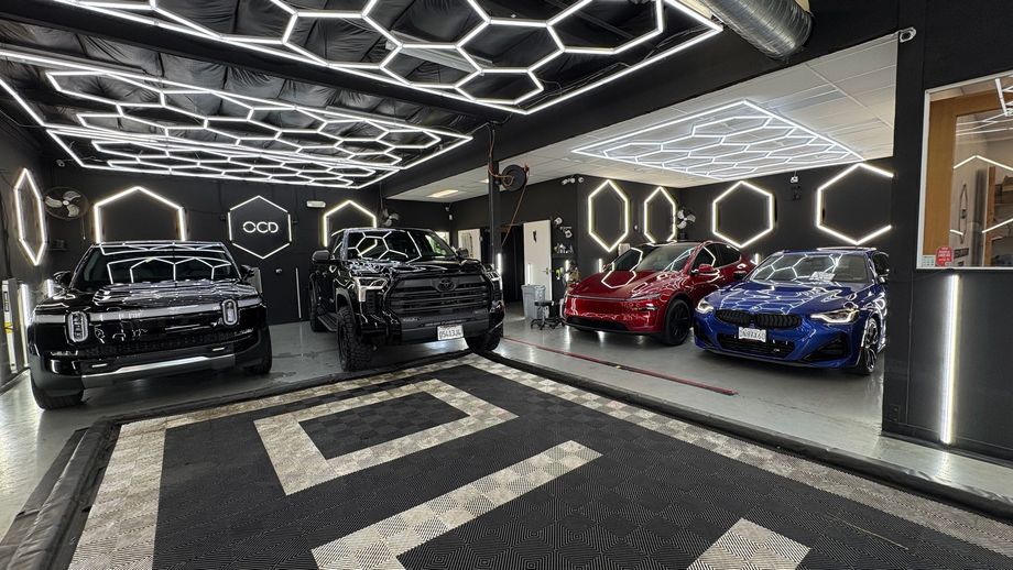 Luxury car showroom with four sports cars under geometric ceiling lights and patterned floor
